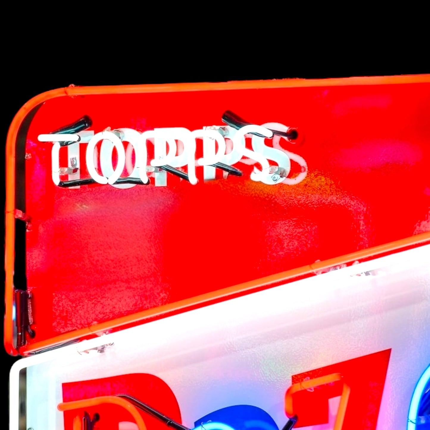 Red and white sign with 'Topps' trading cards branding on a black background
