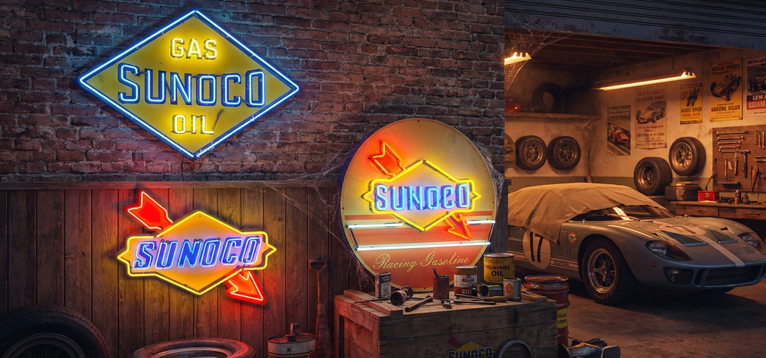 Vintage Sunoco neon signs glowing inside a classic car garage, featuring blue and yellow Sunoco arrow logos, porcelain gas station signage, and a covered Ford GT40 surrounded by retro tools and oil cans — mid-century automotive Americana.
