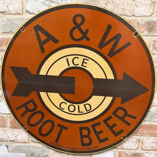 Round A&W Root Beer sign with an arrow on a brick wall background
