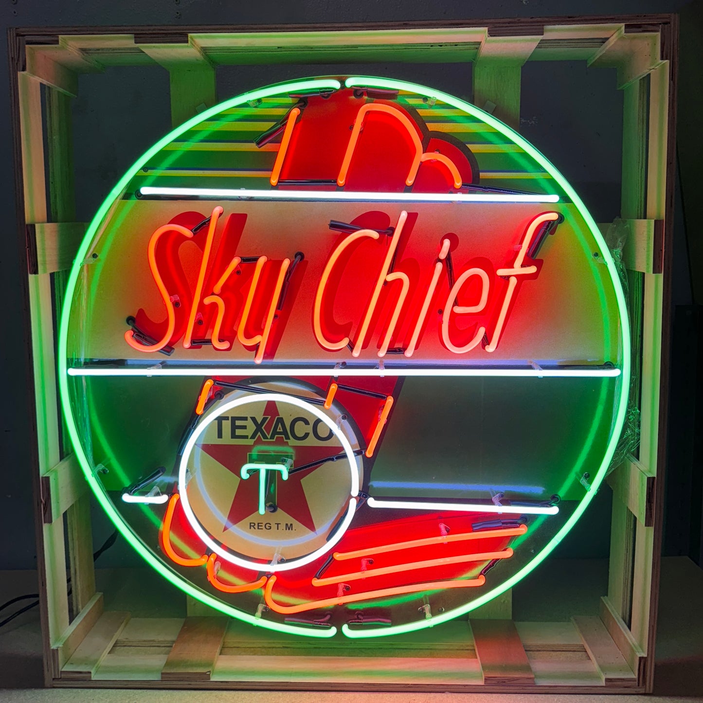 Neon sign featuring 'Sky Chief' and Texaco logo in a wooden crate.