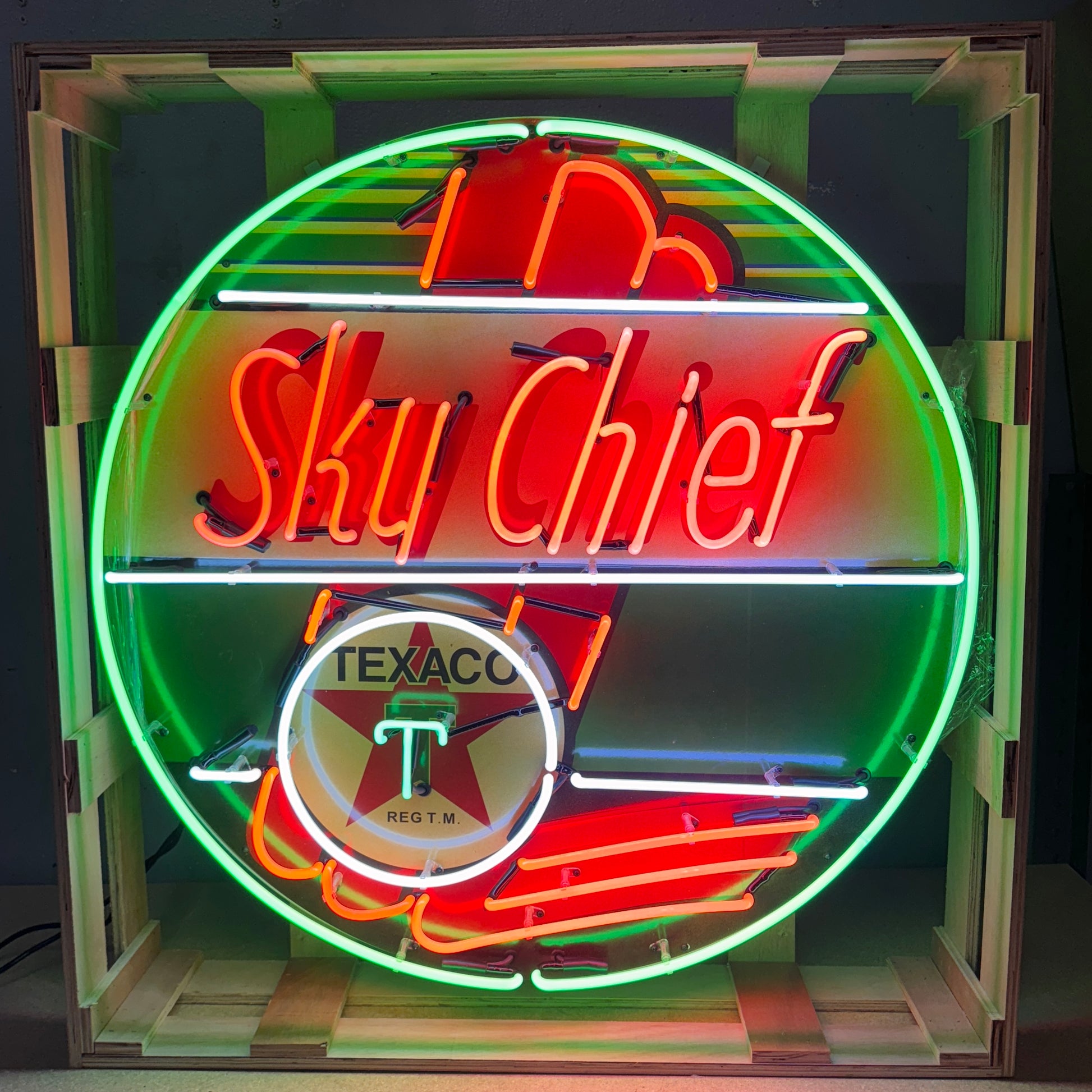Neon sign featuring 'Sky Chief' and Texaco logo in a wooden crate.
